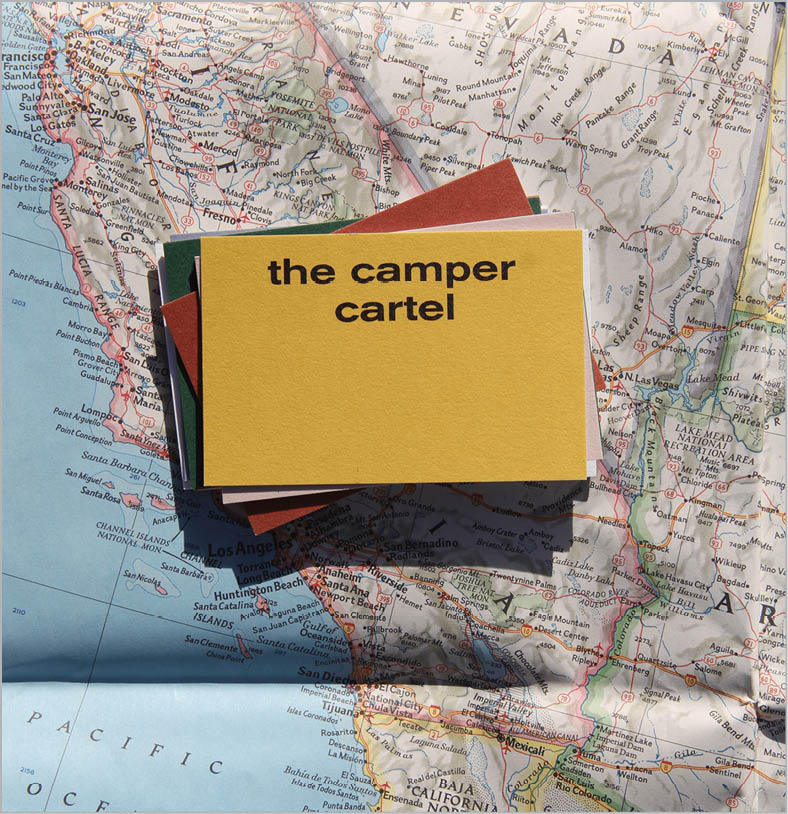 Stack of solid color cards, with top card "the camper cartel" on goldenrod ink, all stacked on road map of California.