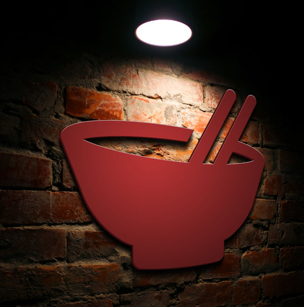 Brick wall with ramen bowl logo lit by overhead lamp