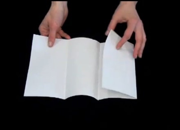 two hands folding blank piece of paper into a four-fold brochure