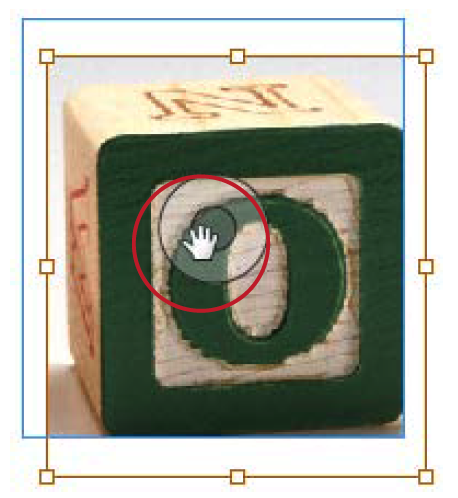 Photo of children's wooden block with green "O" on its face is selected, with brown bounding box showing as grabber hand (highlighted in image with red circle) reorients it within its container graphics frame.